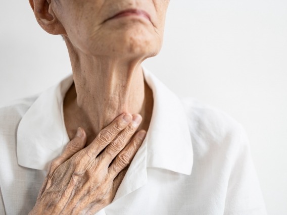 an elderly woman touching her neck
