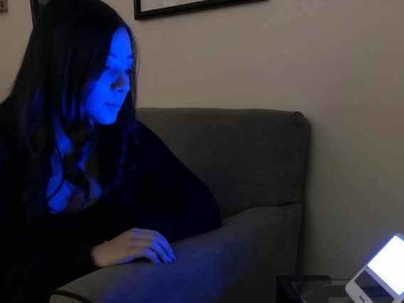 a person staring at a machine emitting blue light
